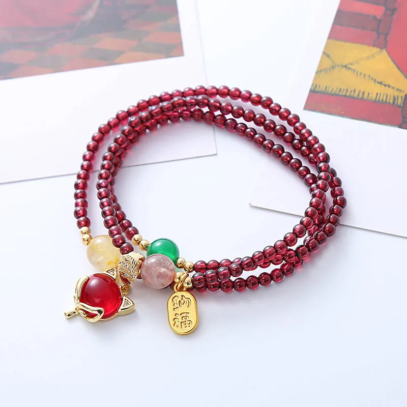 Purplish red rope bracelet with a detailed natural garnet fox pendant and adjustable tie closure.