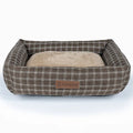 Grey plaid square cloth dog bed for medium-sized dogs on a wooden floor.