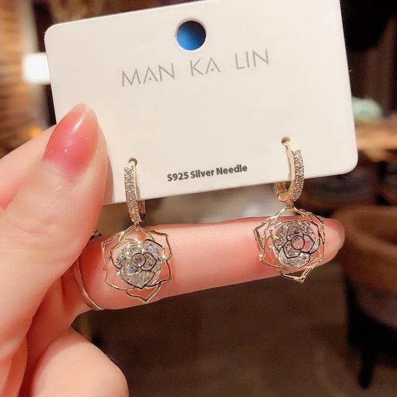 A pair of women's geometric copper earrings with a rose design and small zircon stone accents.