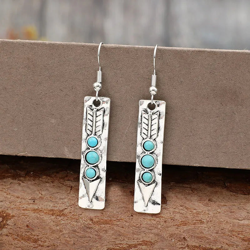 Silver long drop earrings with turquoise inlay and a geometric shape.