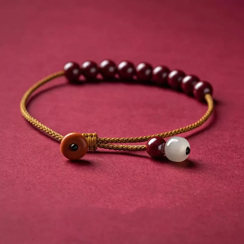 Close-up of a hand-woven geometric bracelet made from cinnabar and Hetian jade stones.