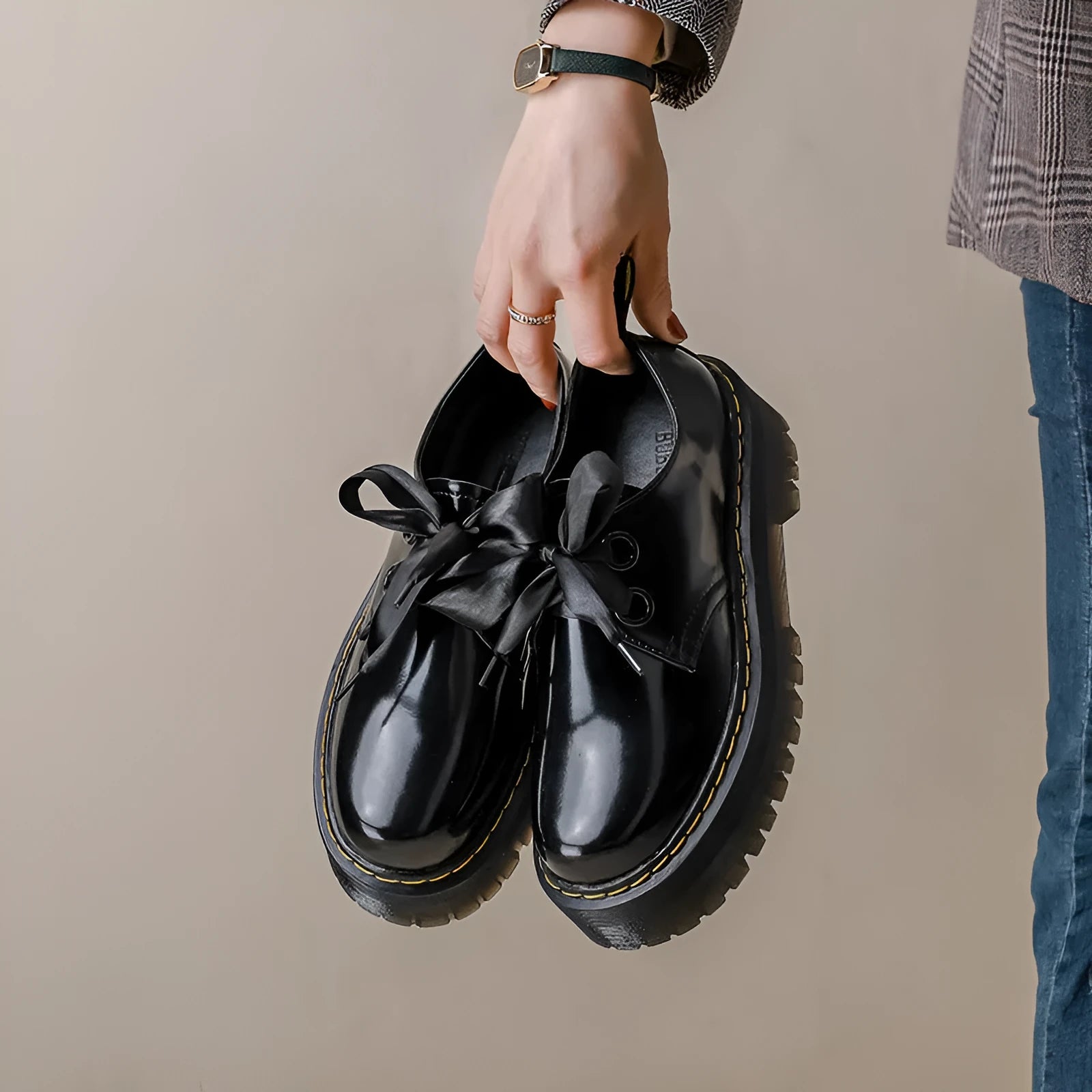 Women's black leather shoes with thick soles, cross straps, and ribbon lacing shown from side view