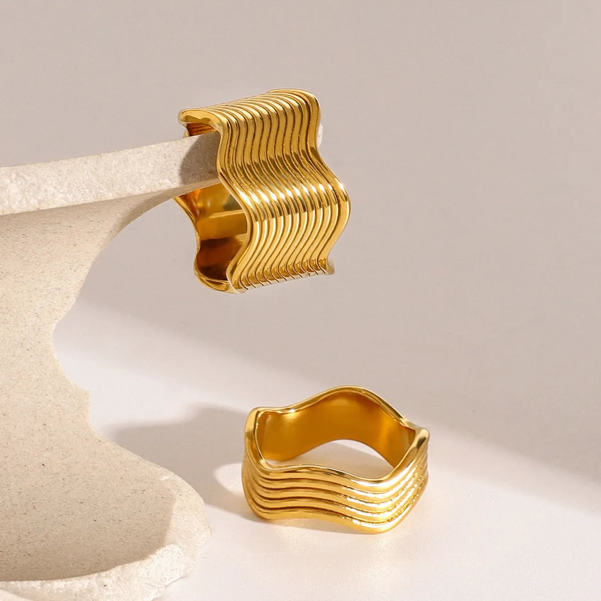 Stainless steel wide band ring with a geometric wave pattern design in an electroplated finish.