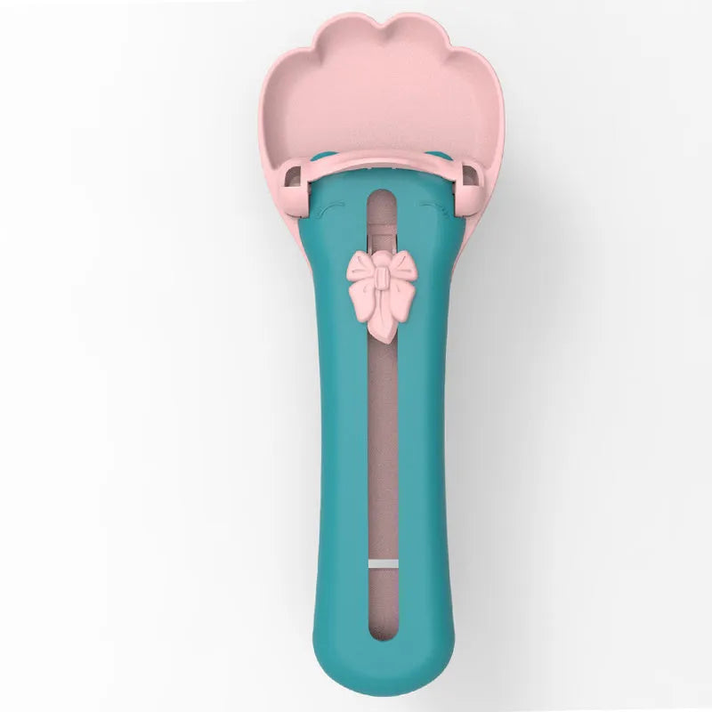 Green and pink pet food scooper spoon with squeezer handle and extruded feeder tip for dispensing treats.