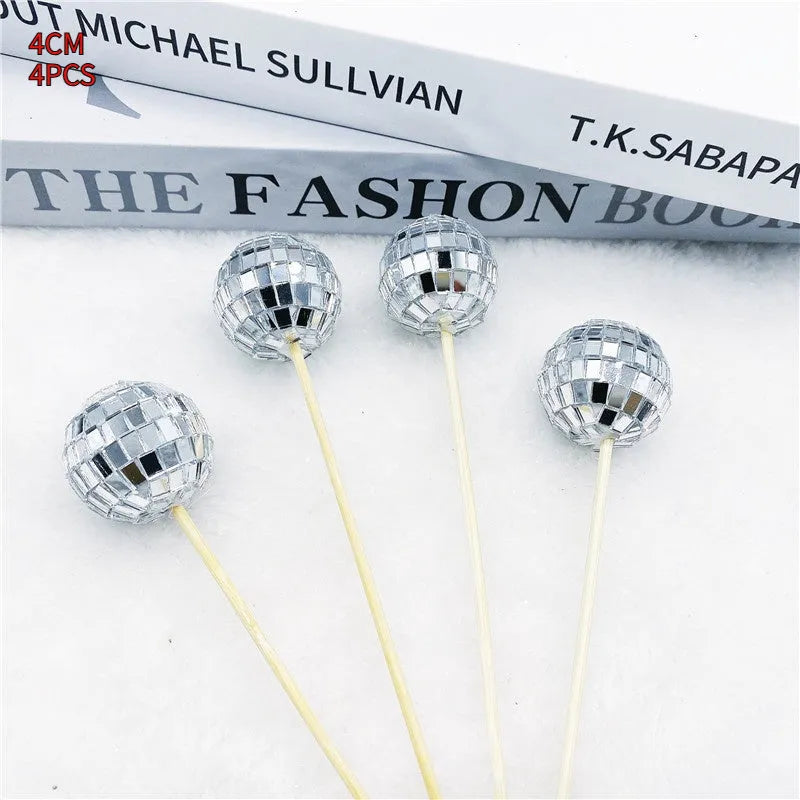 Glass disco ball cake decoration with wooden stick on a cake, showing reflective surface.