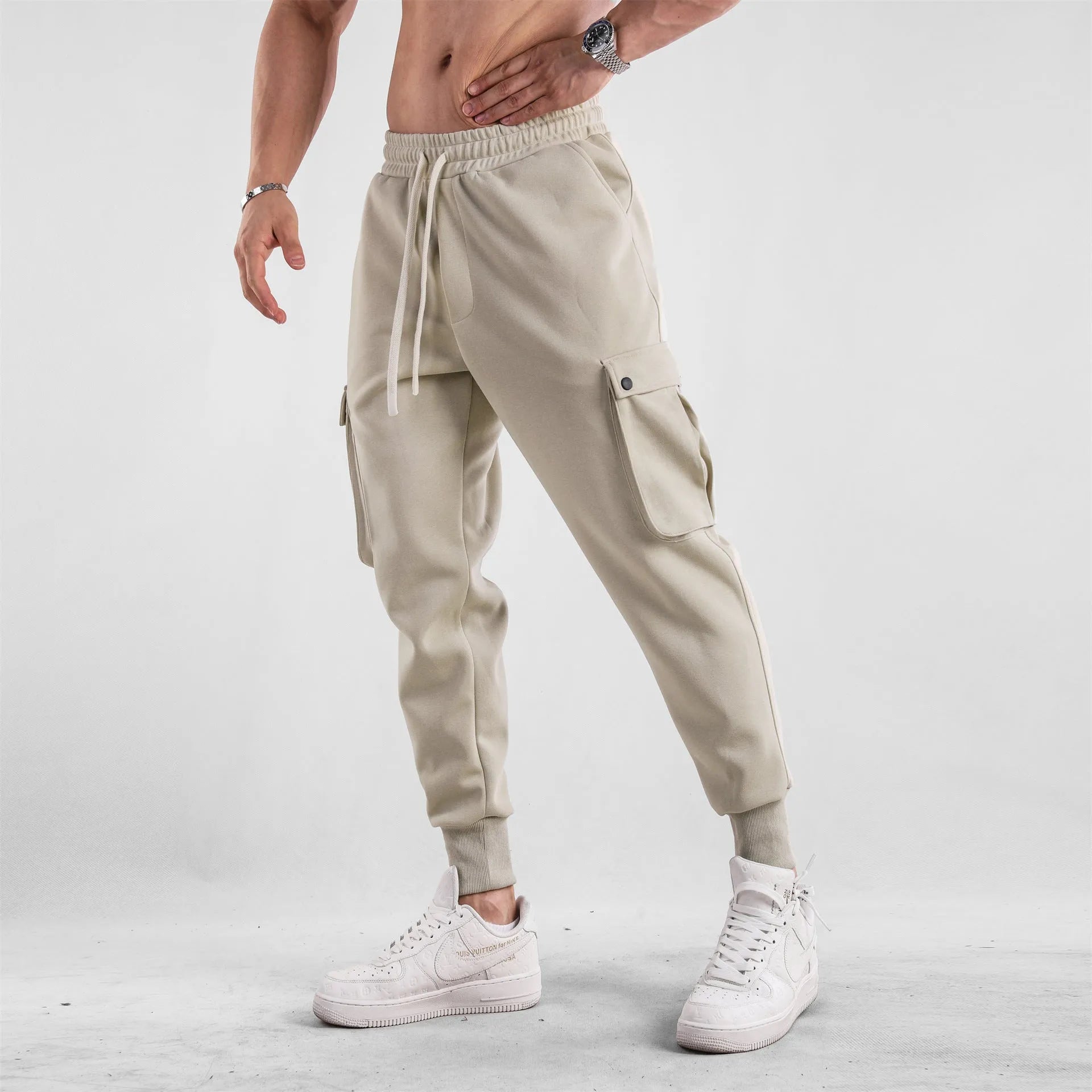 Men's loose fit cotton trousers with ankle-tied cuffs and multiple pockets in a light grey colour.