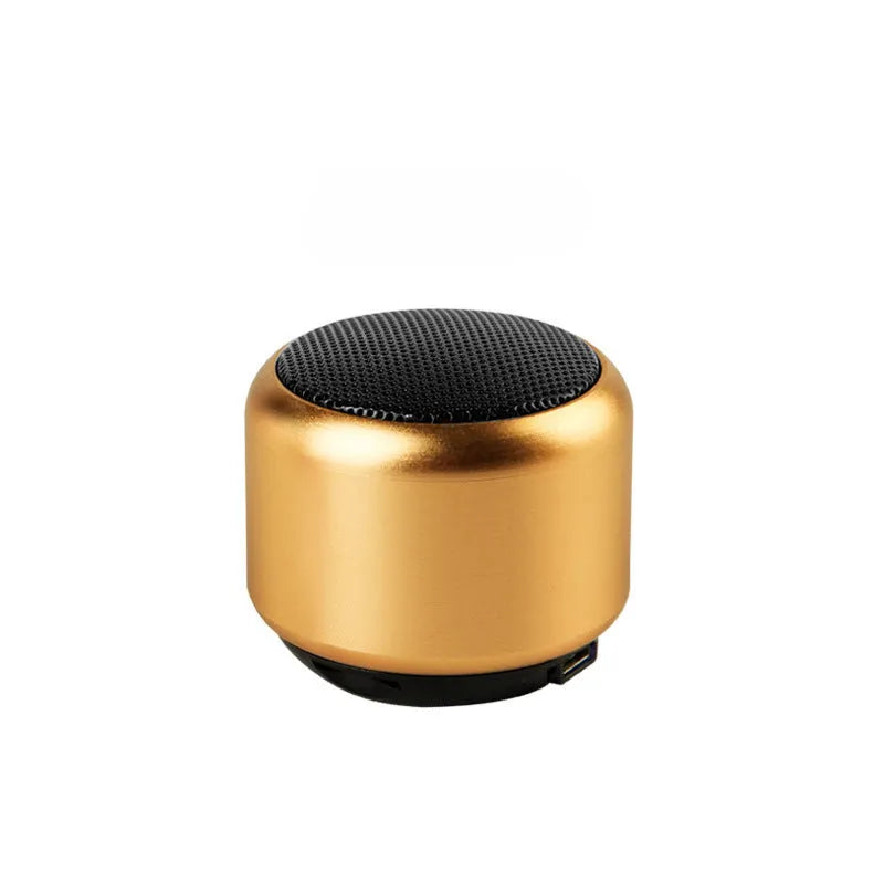 A small portable Bluetooth speaker shown in one of four colour options: black, blue, gold, or pink.
