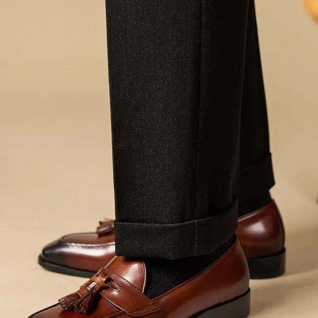 Men's black polished leather tassel loafers on a white background