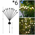 Solar-powered LED firefly lawn light with ground stake inserted in grass