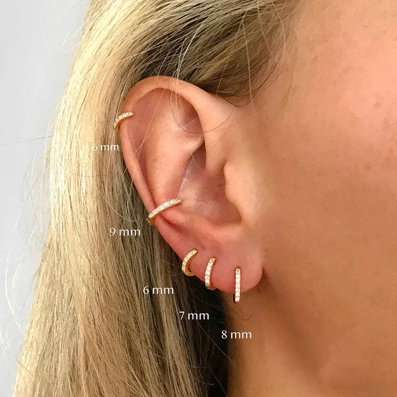 A pair of round gold-coloured stud earrings with a geometric perforated design and central zircon stone.