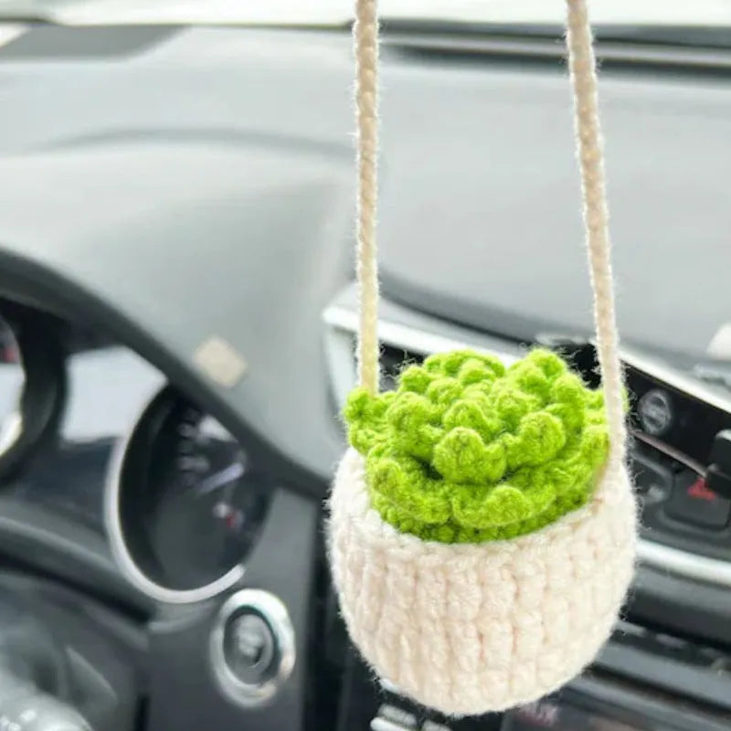 Green and white crochet wool car plant decoration with hanging rope on car dashboard