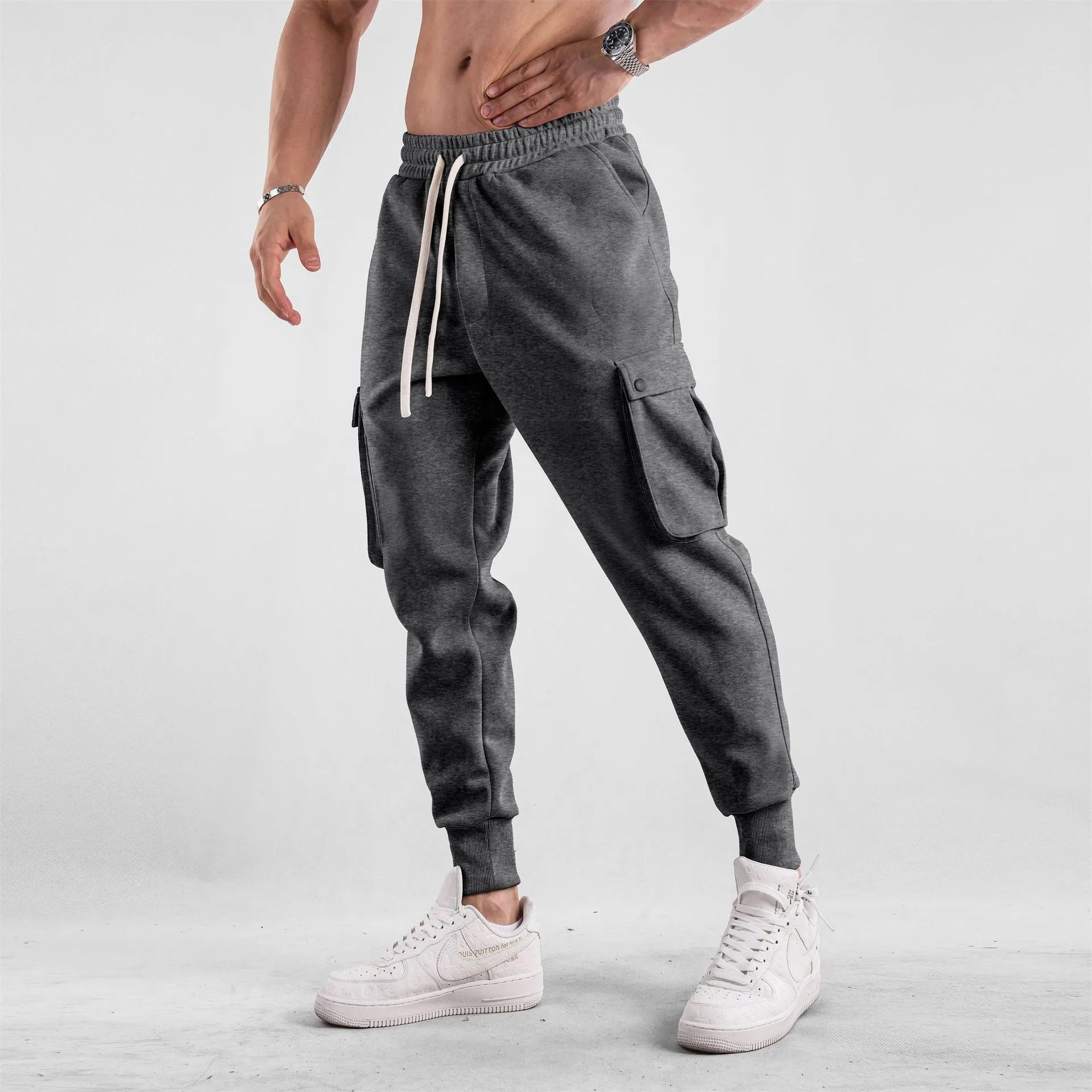 Men's loose fit cotton trousers with ankle-tied cuffs and multiple pockets in a light grey colour.