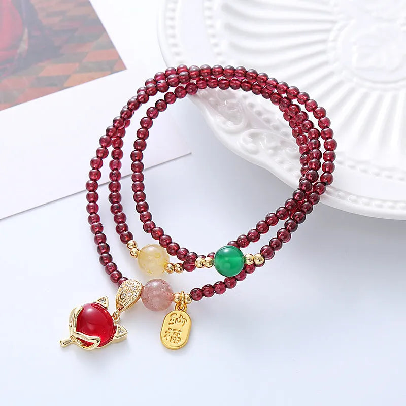 Purplish red rope bracelet with a detailed natural garnet fox pendant and adjustable tie closure.