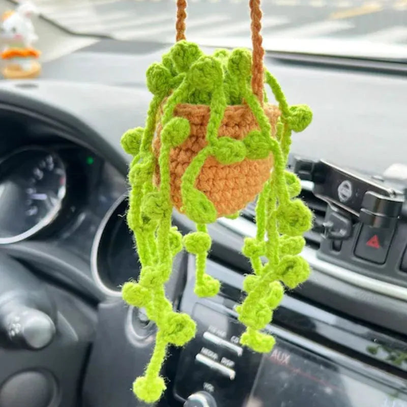 Green and white crochet wool car plant decoration with hanging rope on car dashboard