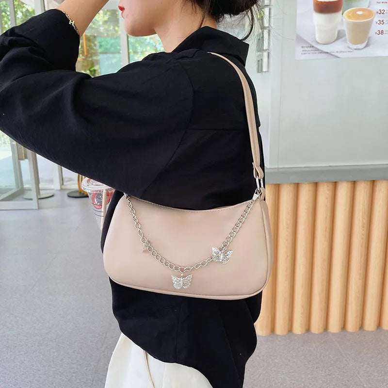Square black PU leather crossbody bag with a butterfly chain strap and external structured pocket.