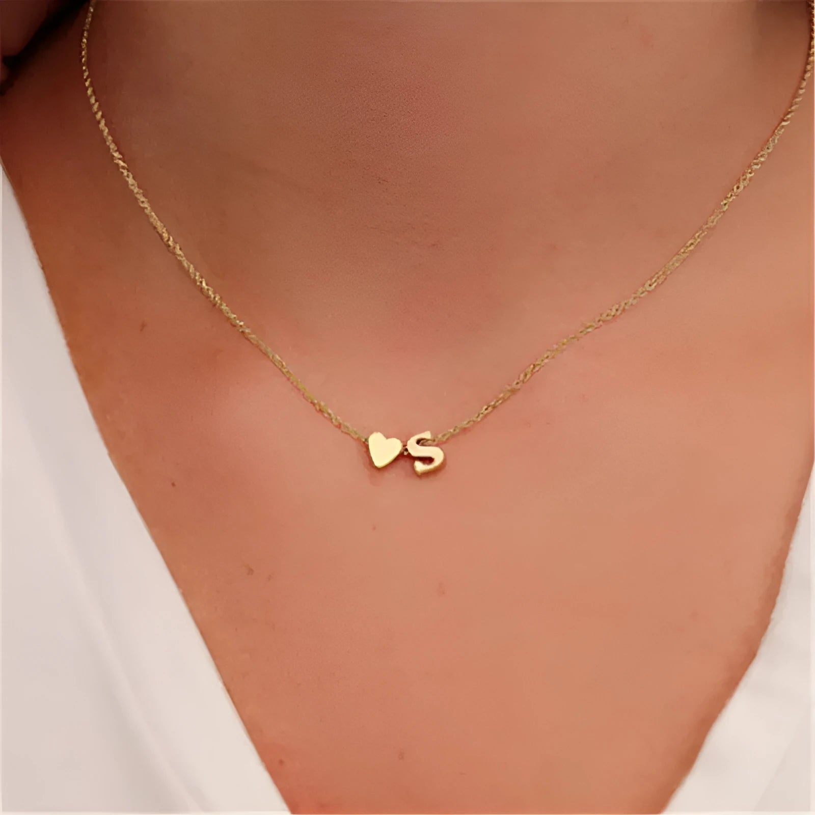Gold alloy peach heart pendant with a letter charm on a chain.