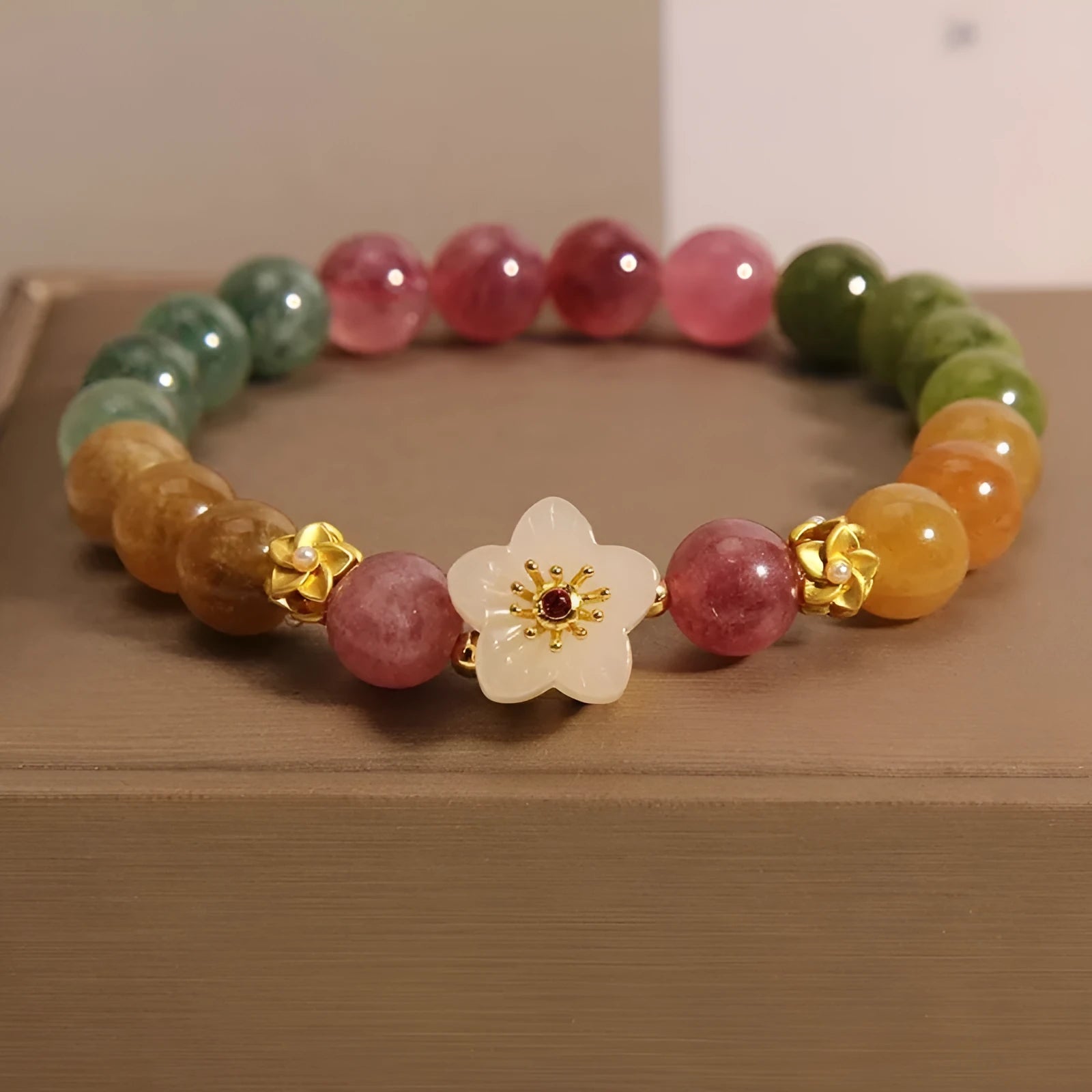 Natural colour tourmaline bracelet with floral beads and geometric design on wrist