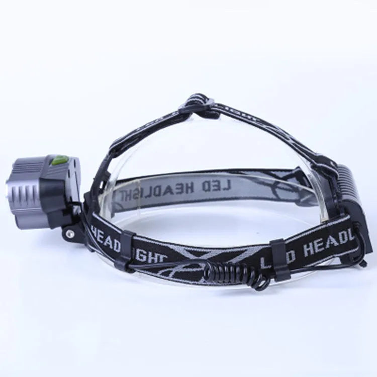 Black head-mounted LED camping torch with adjustable strap and long-range beam shown in outdoor setting.