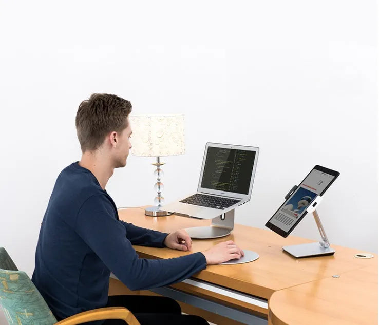 Silver aluminium and ABS folding stand holding a tablet, showing 360-degree rotation and anti-slip silicone pads.