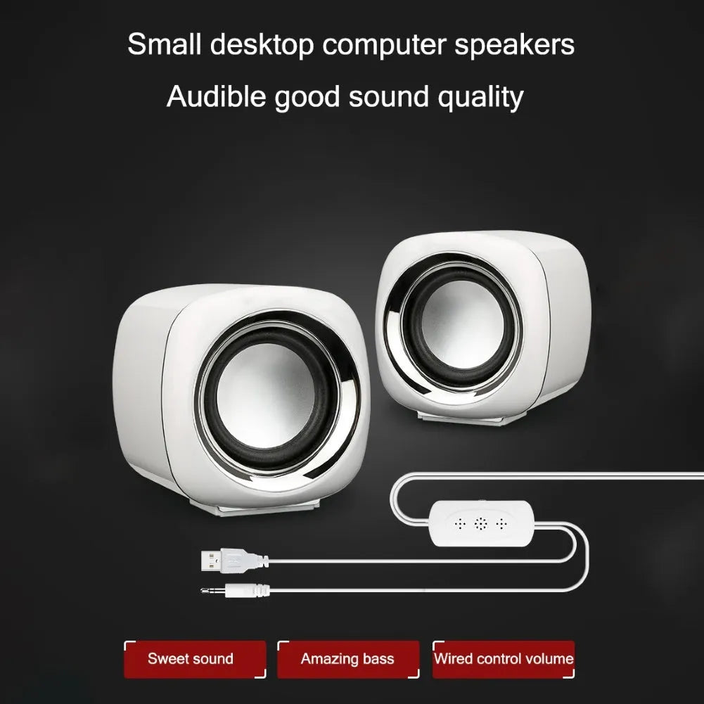 Pair of compact black wired desktop computer speakers with top volume scroll wheel next to a laptop.