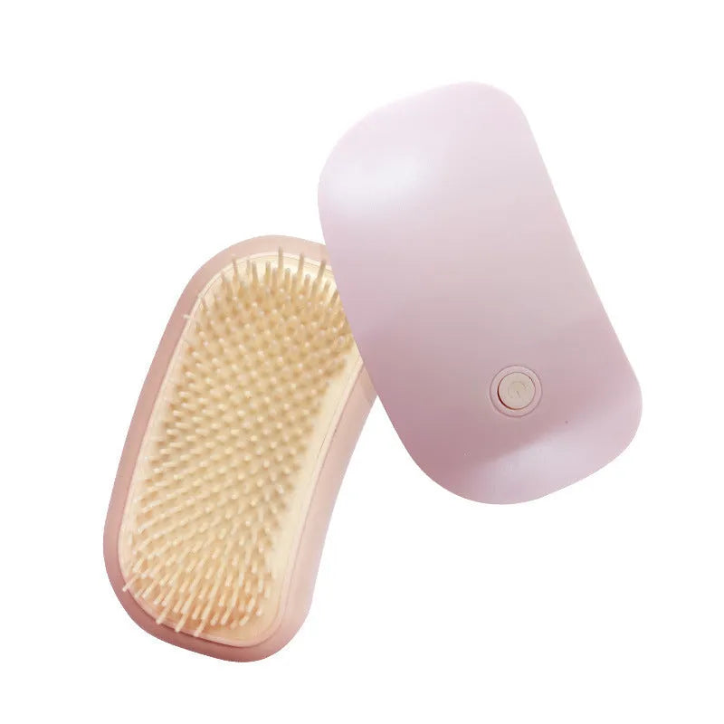 Light pink handheld electric vibration brush for grooming cats and dogs on a white background.