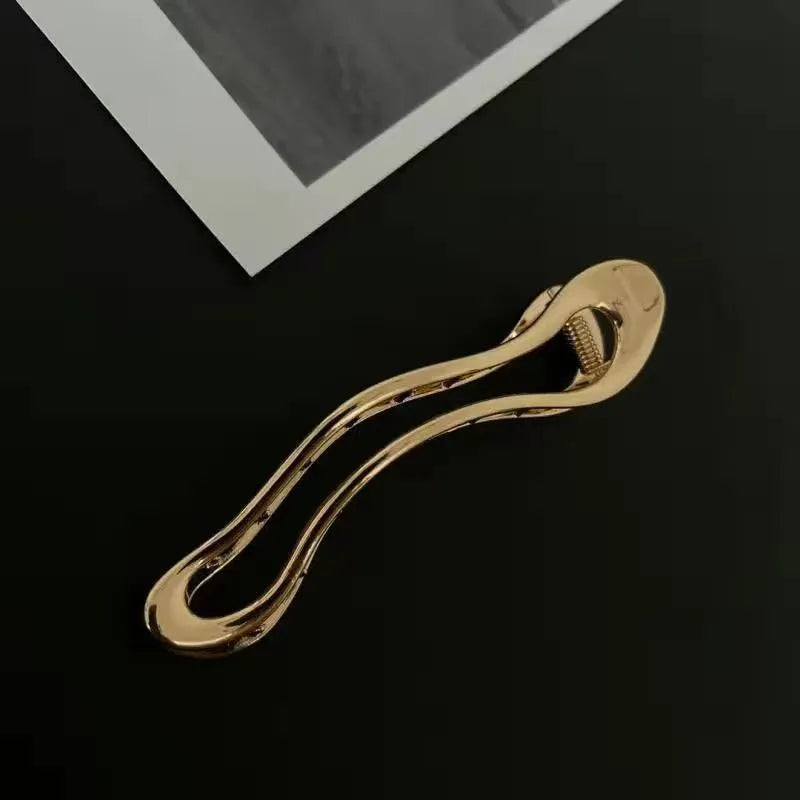Golden zinc alloy hair barrette in an arc shape on a white background