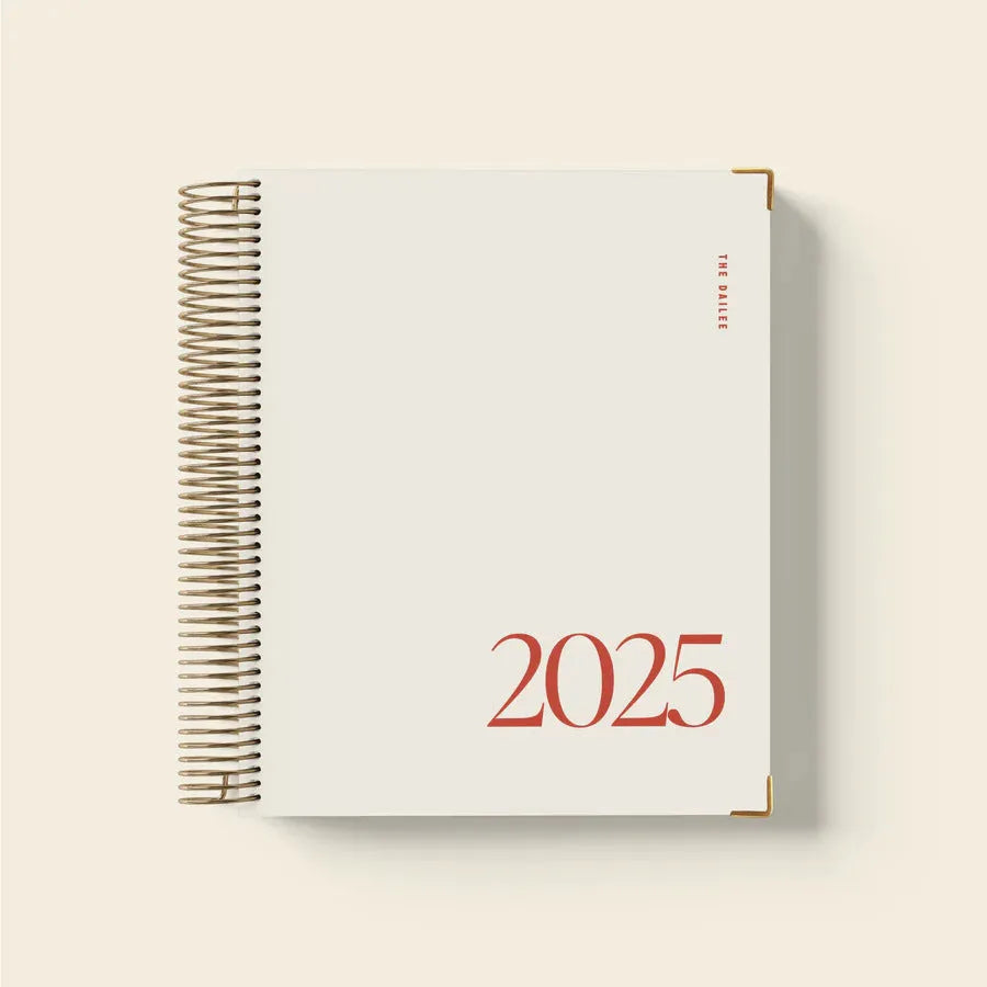 Cherry red coil notebook open on a desk, showing spiral binding and paper pages for scheduling.
