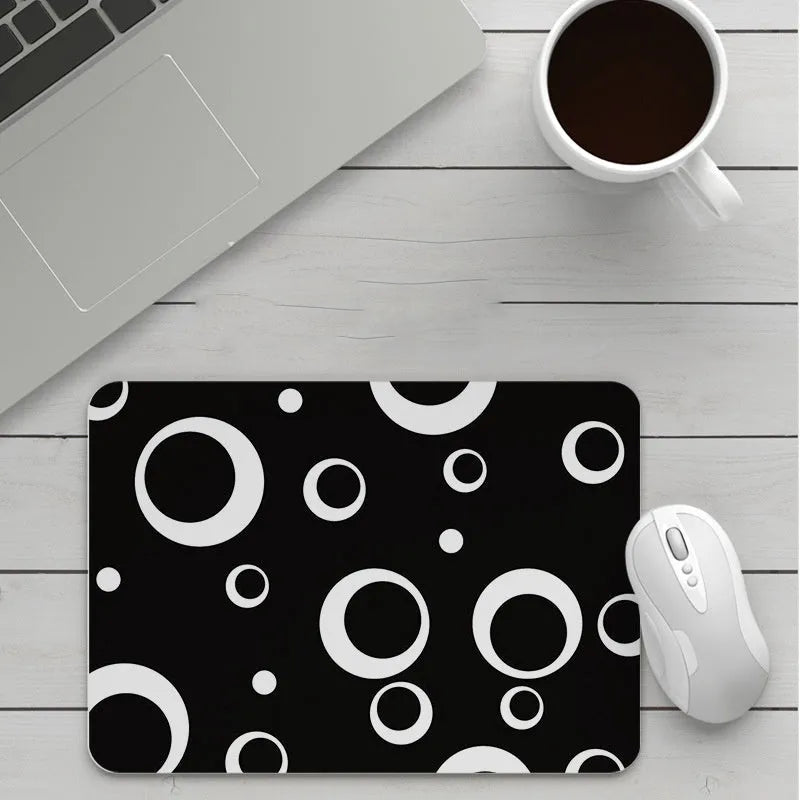Custom cartoon design on a small black thickened mouse pad with stitching, shown on a desk.