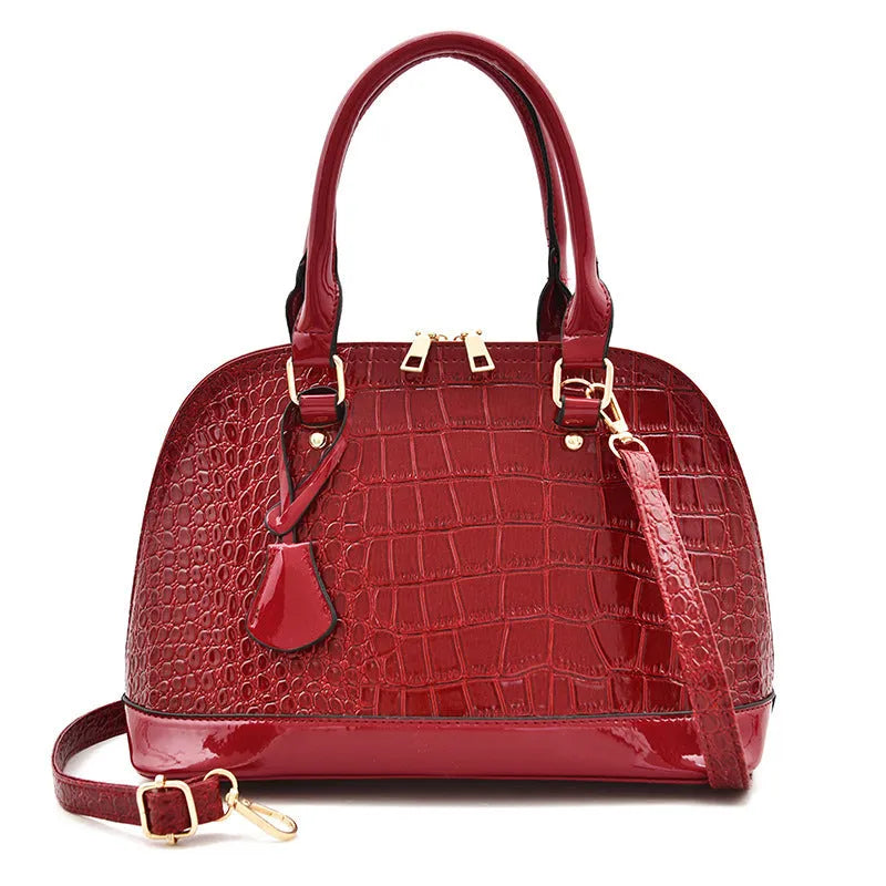 Shiny black PU crossbody bag with a structured shell shape and an adjustable strap.