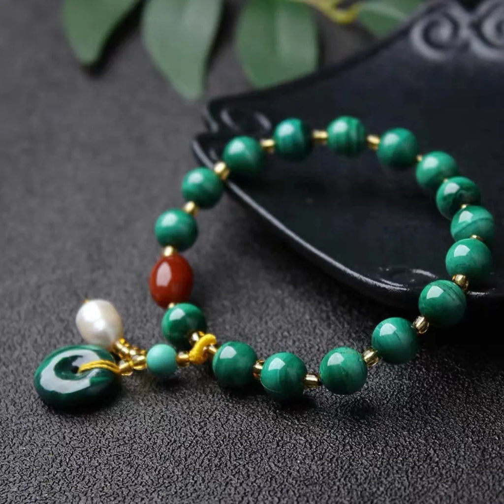 Natural malachite and red agate barrel bead bracelet with silver fittings on a woven elastic cord.