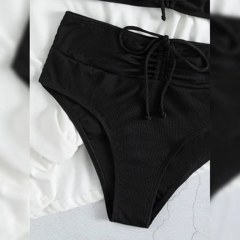 Black high-waisted bikini swimsuit for women with sleeveless top and shorts on a neutral background.