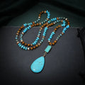 Turquoise blue water drop pendant necklace with geometric shapes on a long ball bead chain.