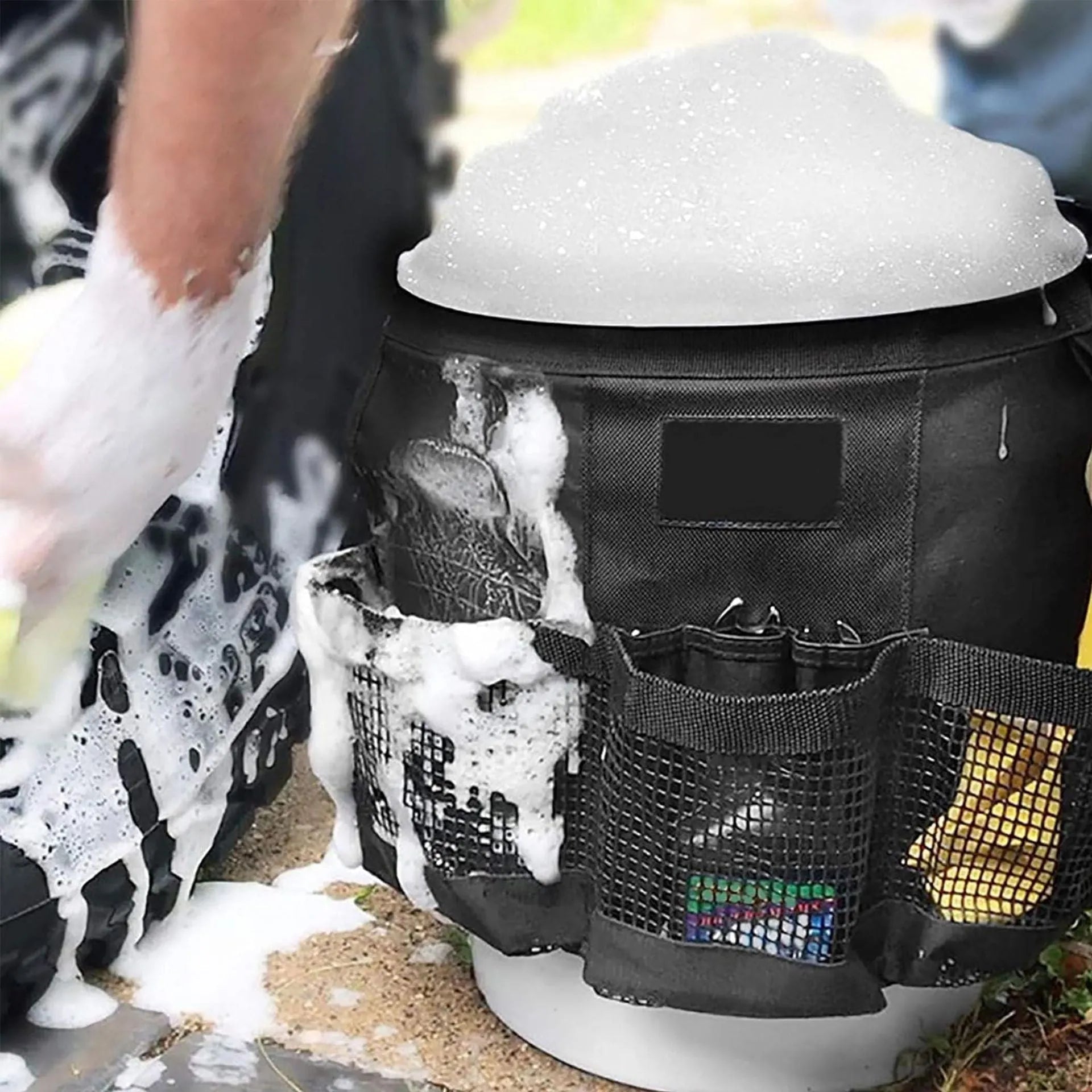 Black cylindrical polyester storage bag hanging on a 5-gallon barrel for outdoor tool organisation.