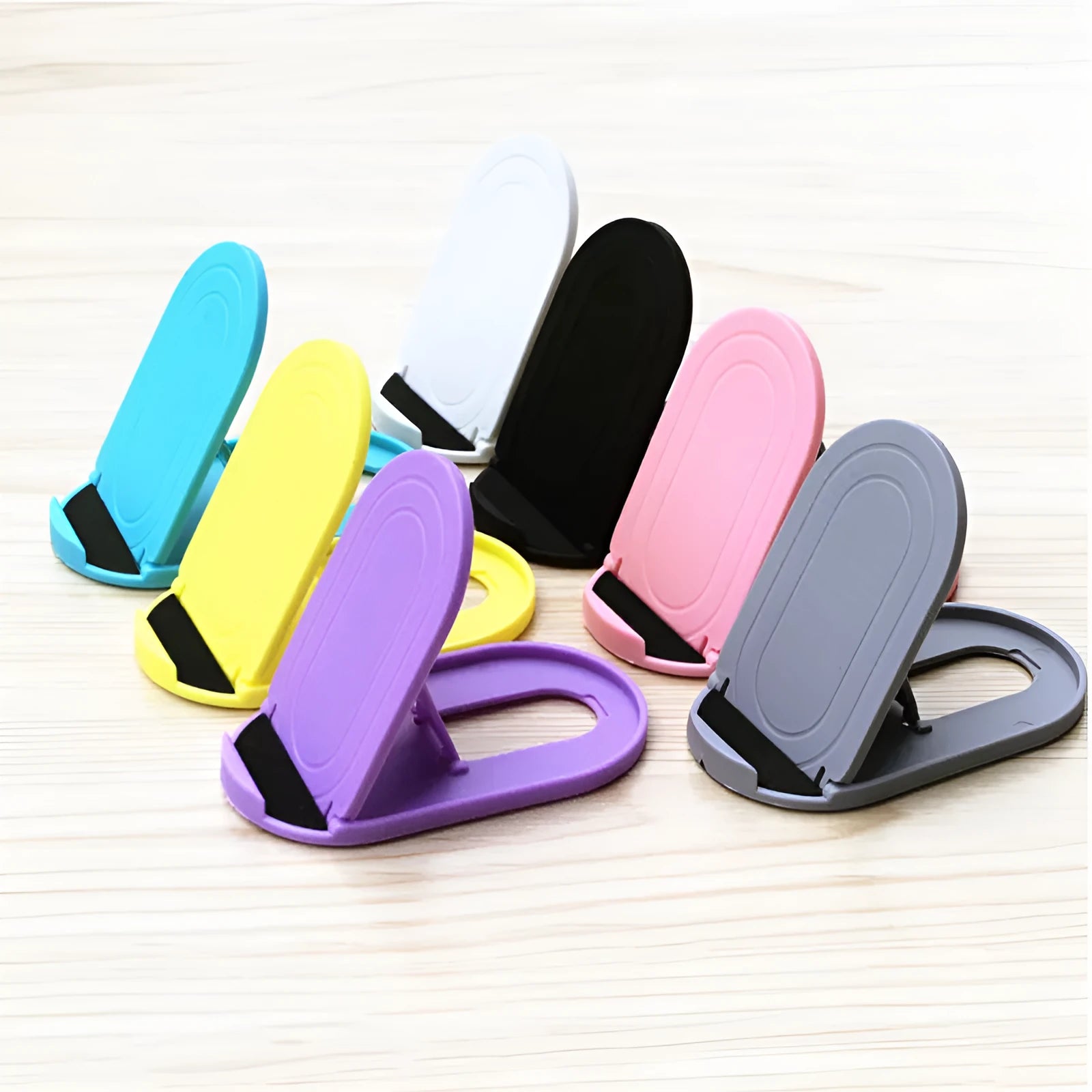 Plastic lazy bracket mobile phone stand in multiple colours on a desk