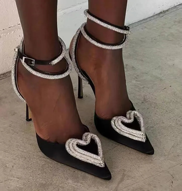Women's pink satin sandal with rhinestone heart decoration, pointed toe, and cross-belt strap.