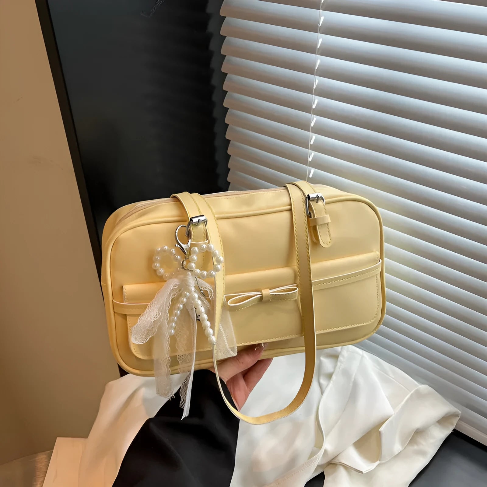 Single-shoulder flap bag in horizontal square shape with bow decoration and internal phone compartment