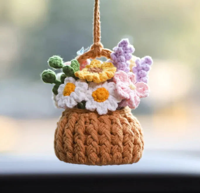 Green and white crochet wool car plant decoration with hanging rope on car dashboard