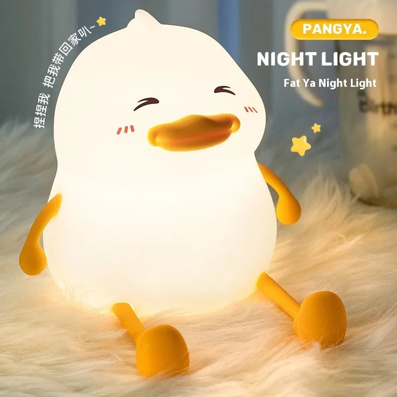 Chubby white rechargeable LED night light with silicone touch top on a wooden desk next to a phone.