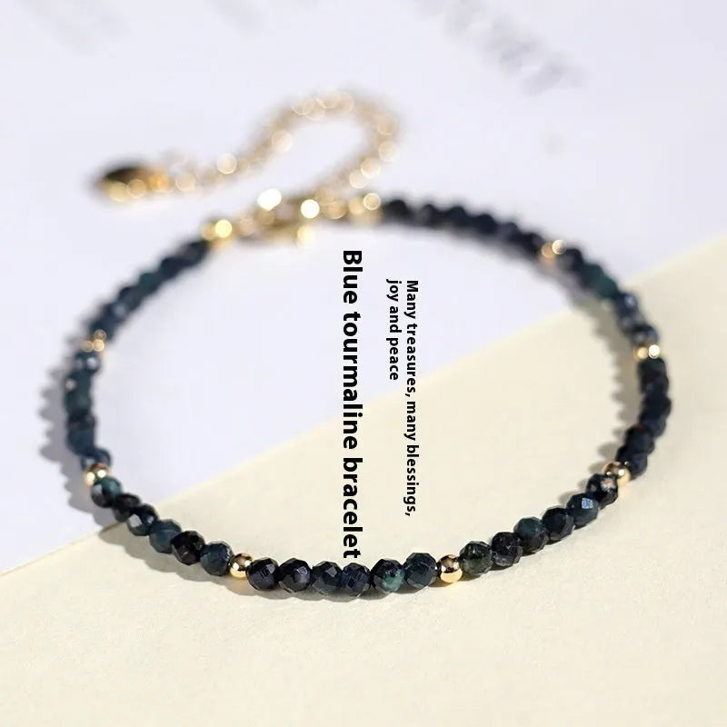 3mm blue tourmaline cut bead bracelet with spacer beads on a wrist