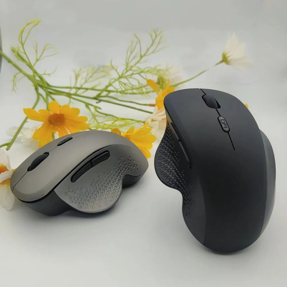 Black wireless laptop mouse with USB-C charging cable on desk next to laptop
