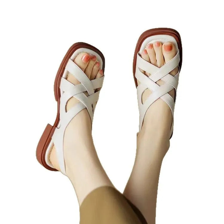 Women's glossy patent leather sandals with a square toe and flat low heel in black.