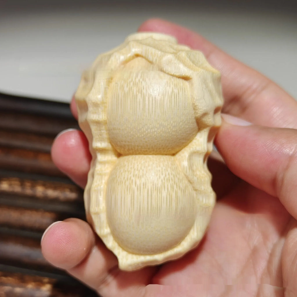 Solid natural bamboo carved peanut ornament with modern simple design on a wooden surface.