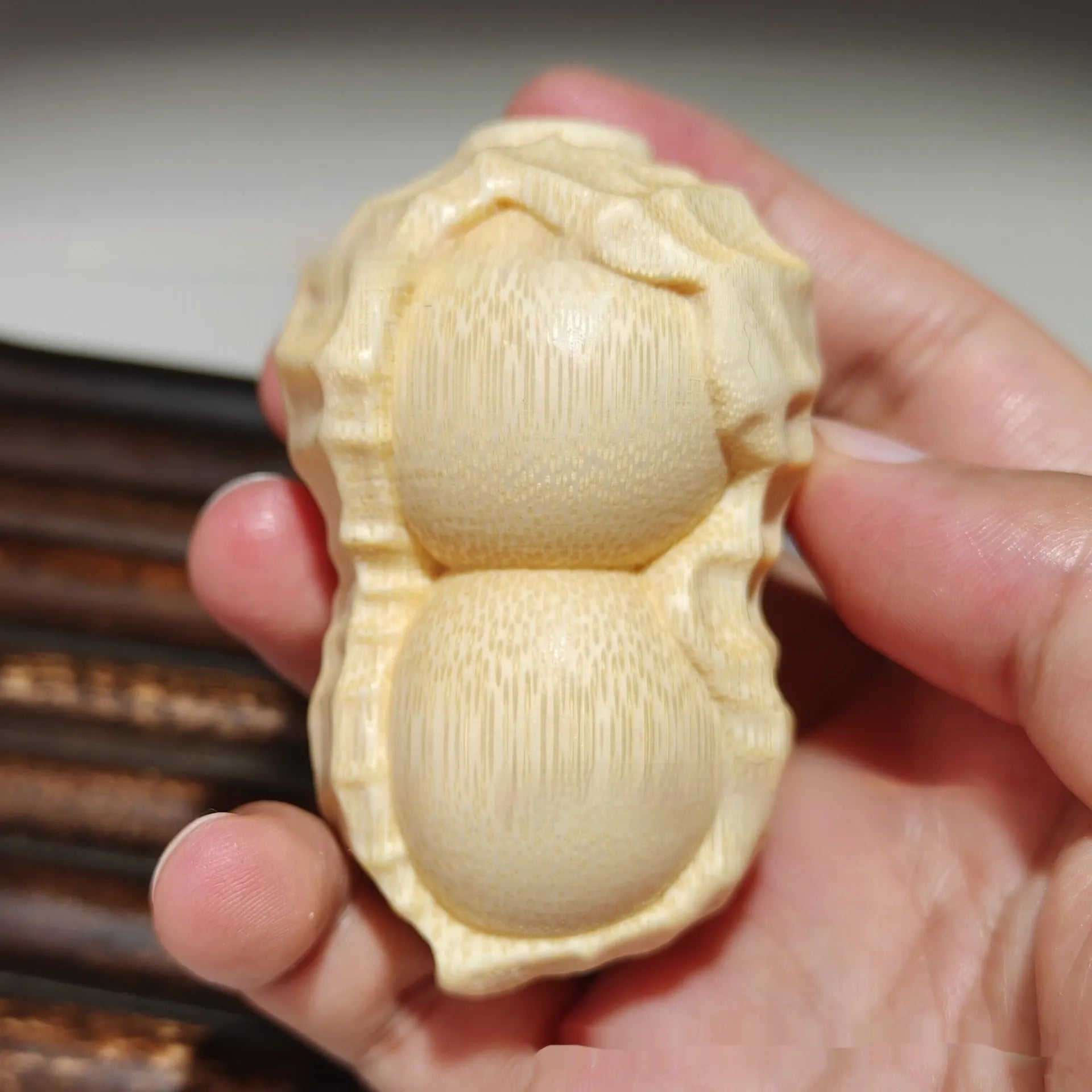 Solid natural bamboo carved peanut ornament with modern simple design on a wooden surface.