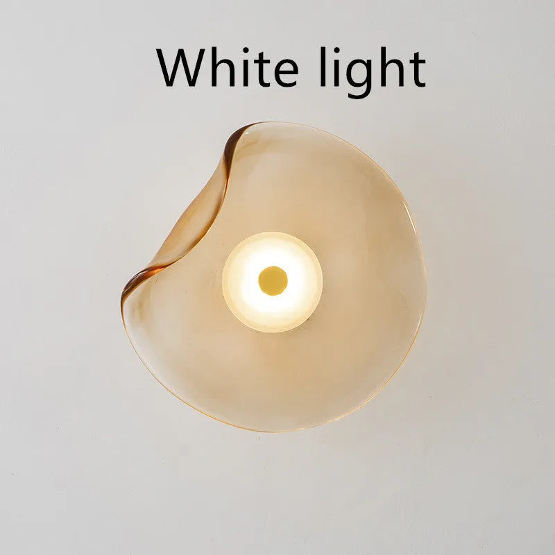 Round glass wall lamp in a choice of colours for bedroom bedside lighting.