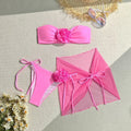 Women's pink tube top swimsuit with 3D flower detail, matching pants, and skirt laid flat.