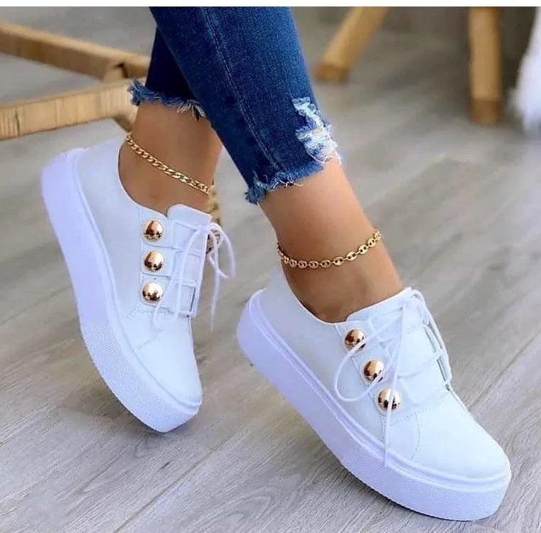 Women's white lace-up flats sneakers with silver rivet details on the low upper and a round toe.