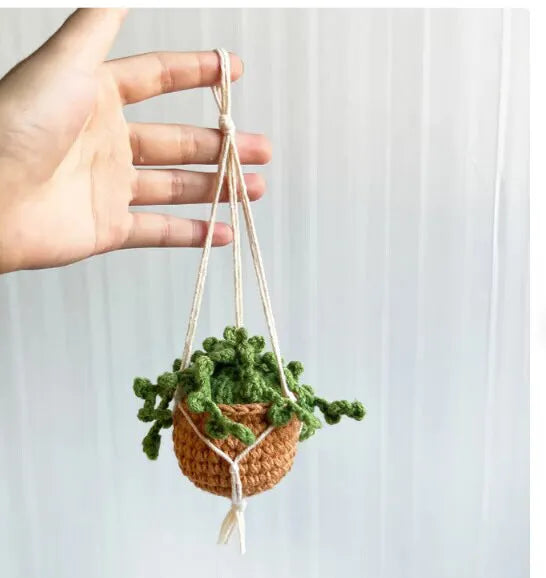 Green and white crochet wool car plant decoration with hanging rope on car dashboard