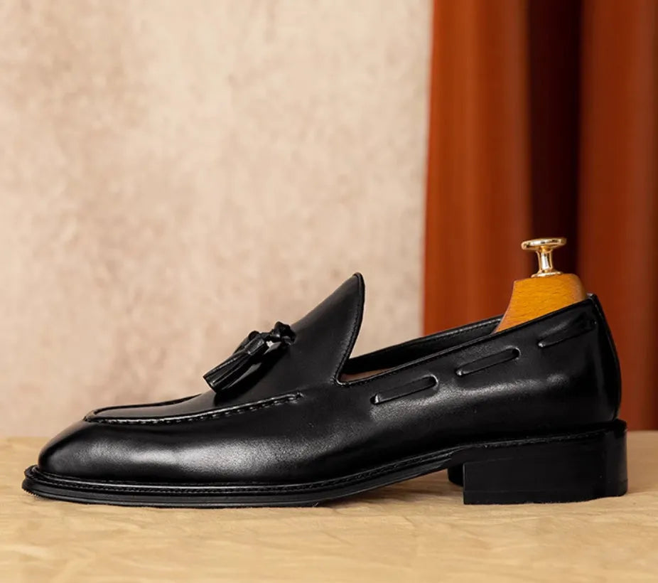 Men's black and brown British-style leather slip-on loafers showing polished leather upper and rubber sole