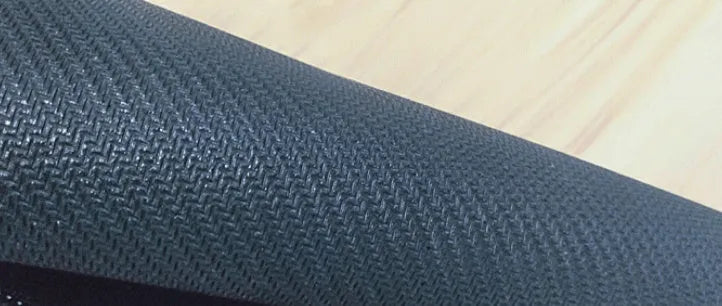 Large black rubber desk mouse pad with a printed geometric pattern, shown on a wooden desk.