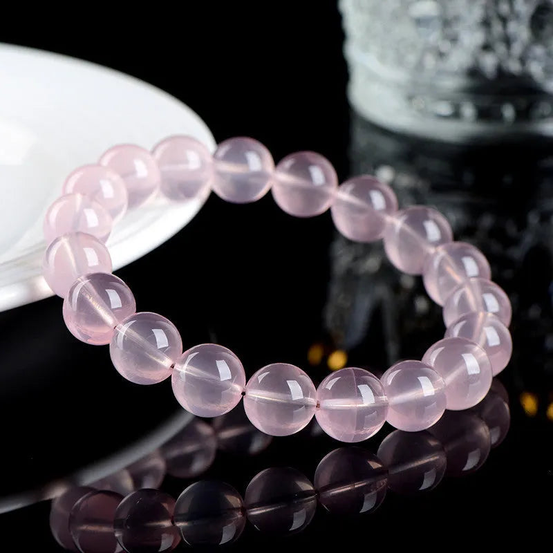 Close-up of a polished natural starlight crystal round bead bracelet in pink, showing single circle design.